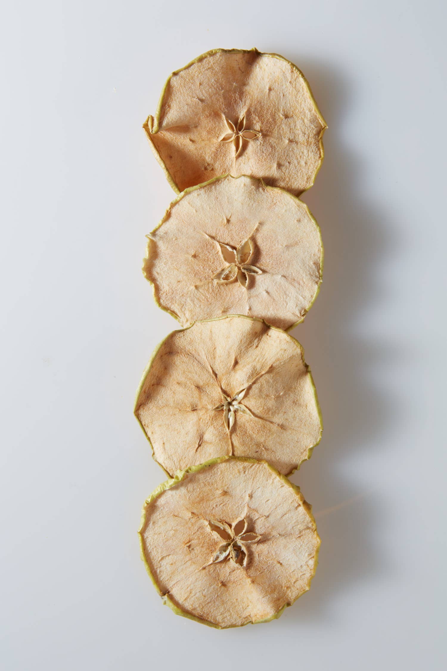 Dardimans California Crisps crispy apple slices snack on a white plate with a few apple slices nearby.