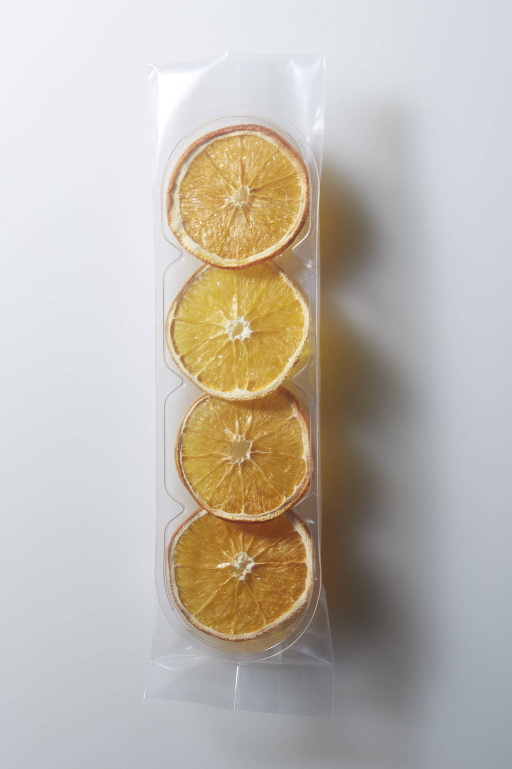 Three dried orange slices in a clear plastic bag on a white background