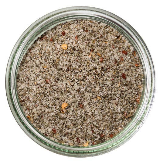 Close-up of a glass jar filled with a spice mix on a white background