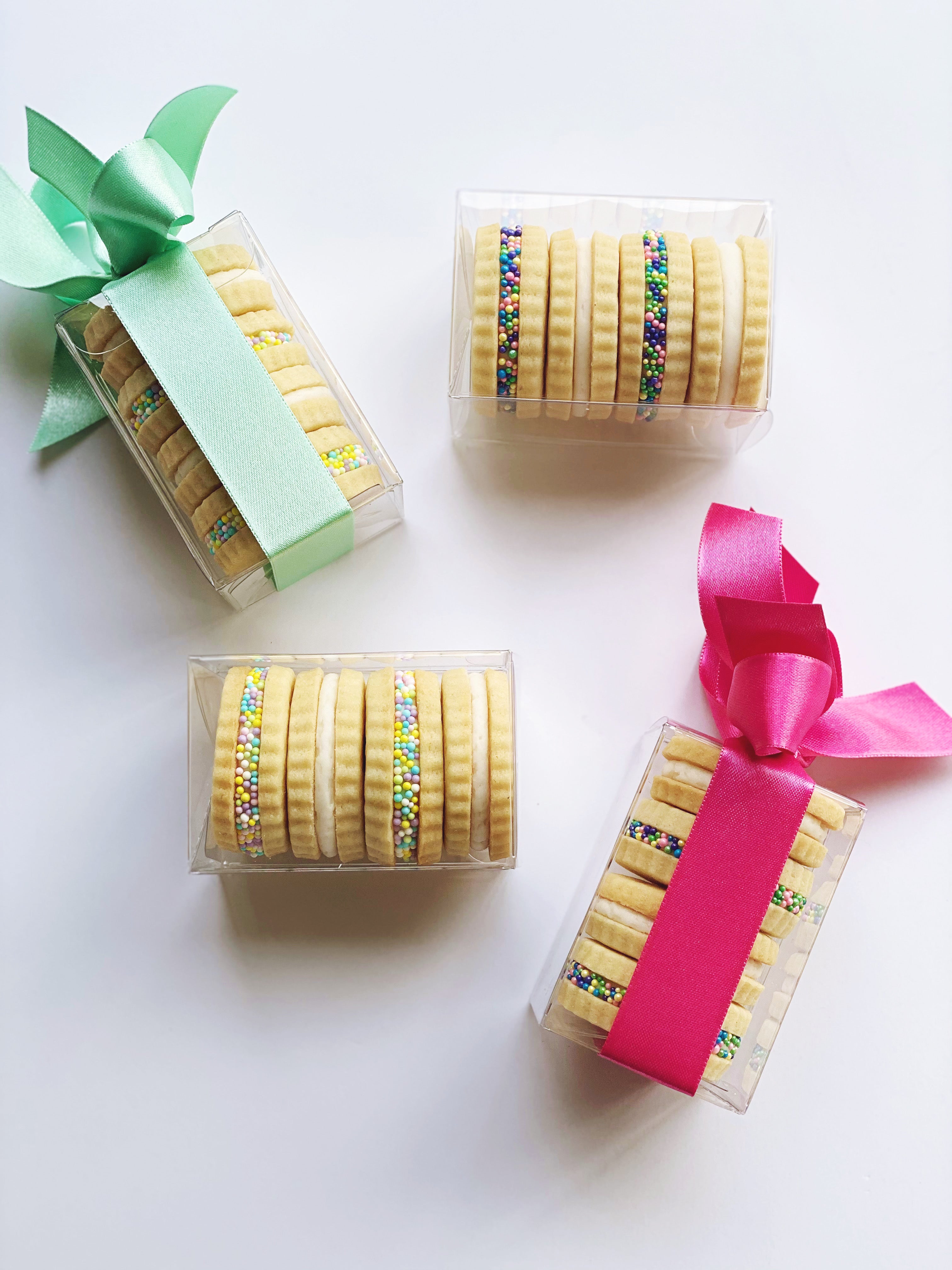 Assorted Poppins & Post buttercream sandwich cookies in four boxes, featuring colorful frosting and cookie layers displayed on a white background.