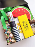 Gift box with colorful popcorn, striped pencils, and a chocolate bar.