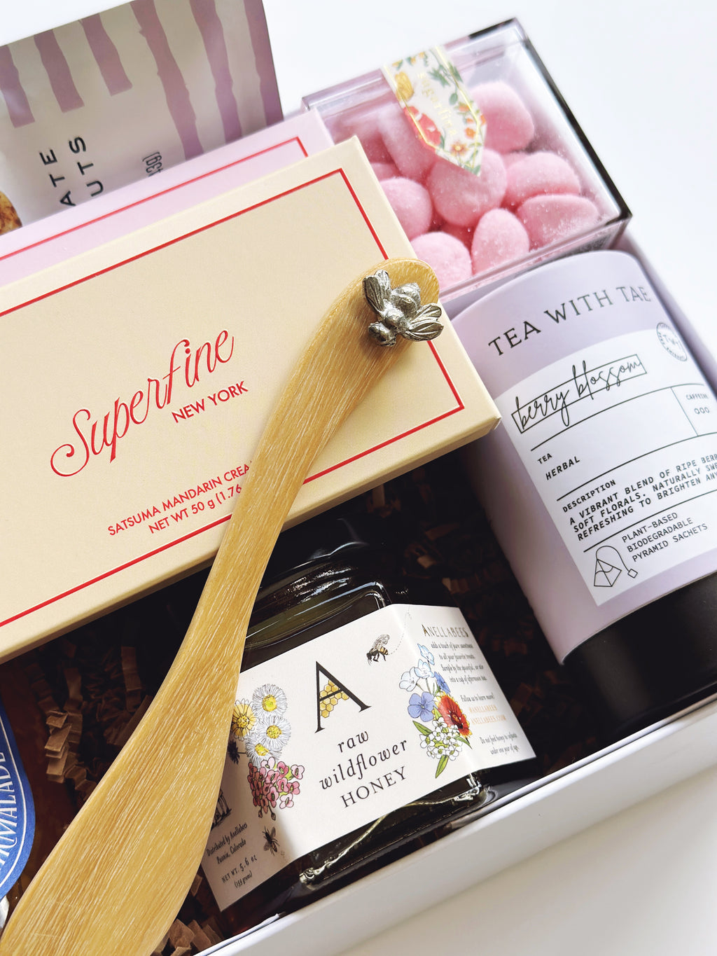 Gift box with wooden spoon, tea,  sugarfina candy and honey in a close-up shot