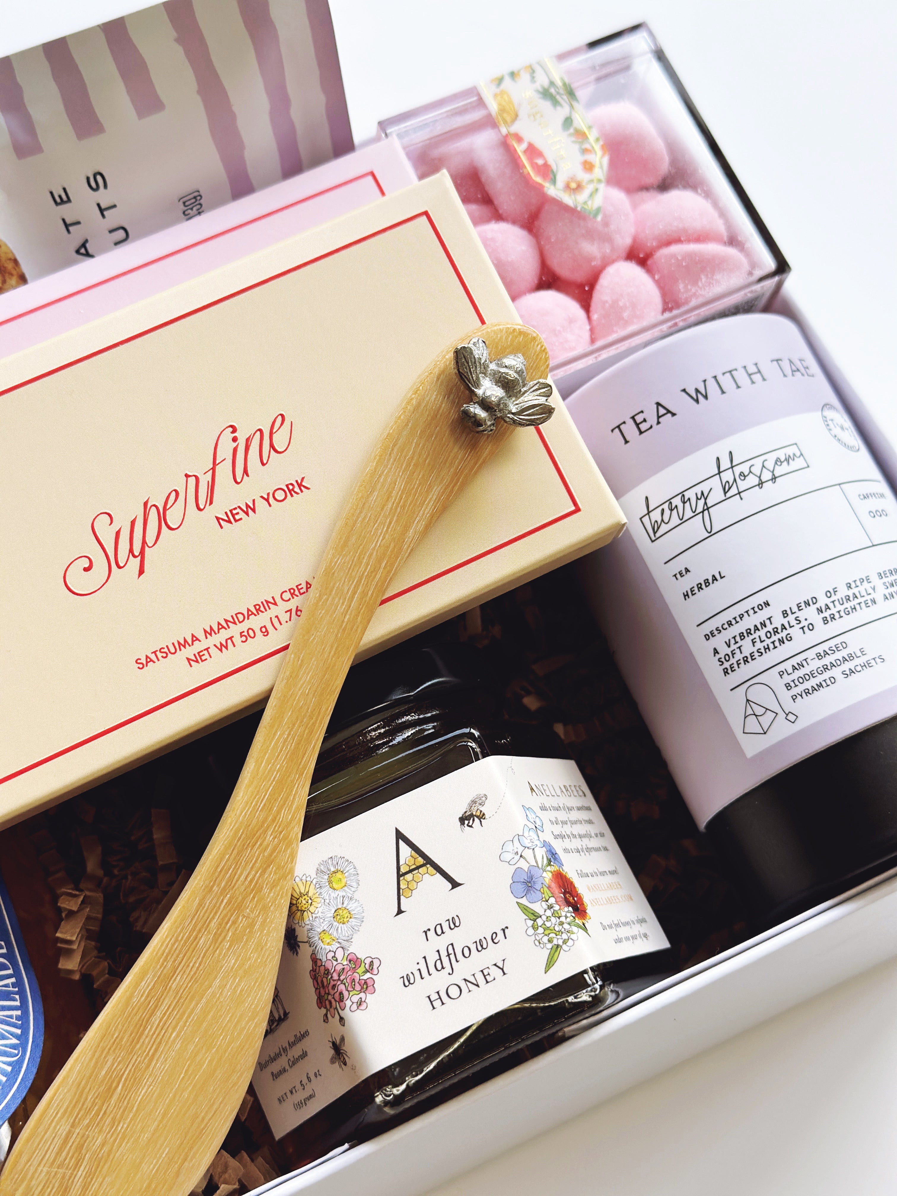 Gift box with wooden spoon, tea,  sugarfina candy and honey in a close-up shot