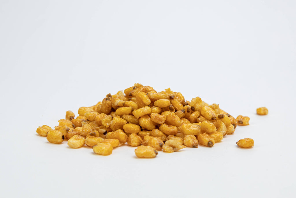 A small pile of golden-brown roasted corn kernels on a clean white background.